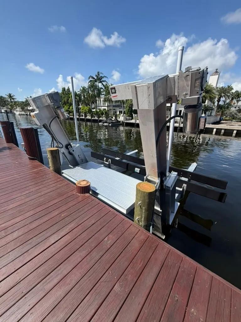 Side view of a ribbed aluminum boarding platform beside a Fort Lauderdale boat lift column and motor