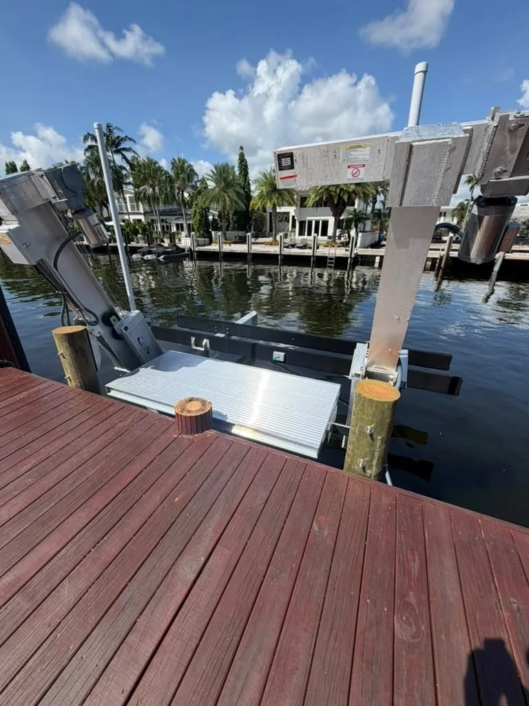 Close view of an aluminum boarding platform spanning two boat lift beams with bunks beyond