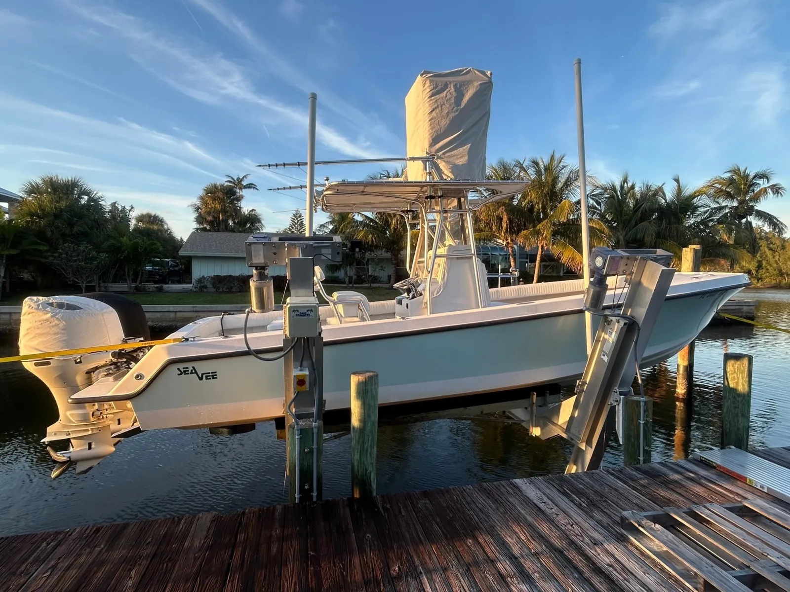 A center-console boat raised out of the water on a four-post lift at a South Florida canal home