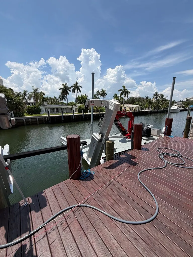 South Florida Seawall barge with a red knuckle-boom crane alongside a Riviera Isles dock