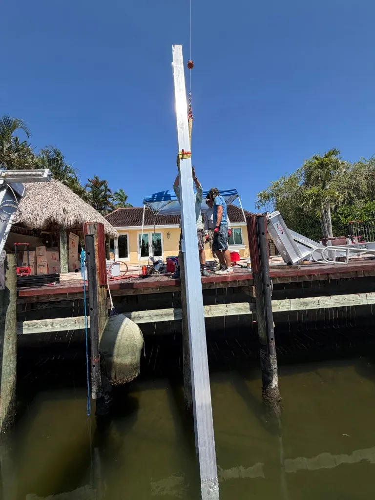 Crew on a Riviera Isles dock guiding the main aluminum boat lift beam from the crane line